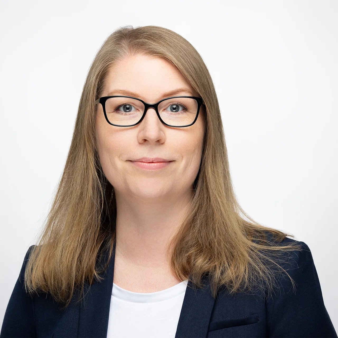 Světlevlasá žena s brýlemi, v bílém tričku a tmavém saku. Byznys portrét na bílém pozadí, čtvercový formát
