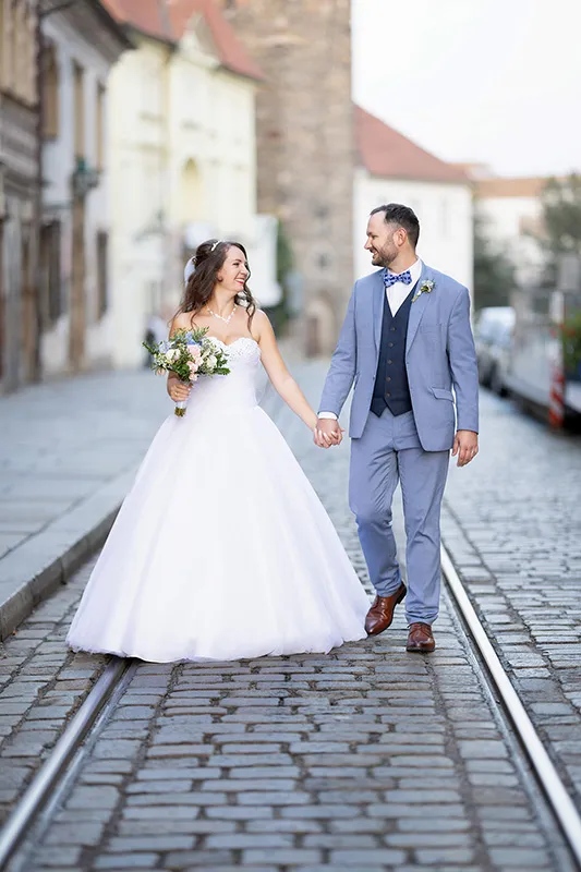 Nevěsta a ženich dívající se na sebe při procházce v historické části Plzně