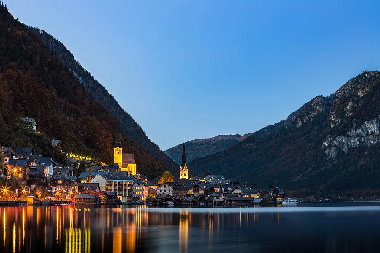 Ikonické panorama městečka Hallstatt v rakouských Alpách se zrcadlící se hladinou jezera Hallstätter See při soumraku.